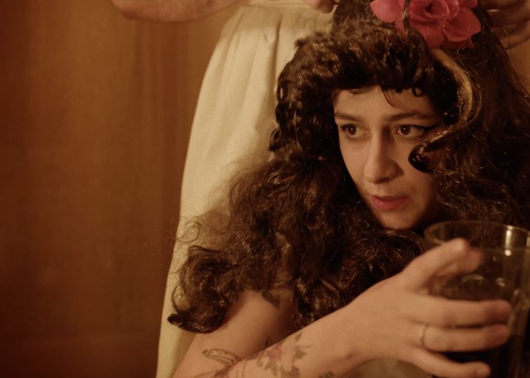 Peluca rizada y flor roja en el pelo.