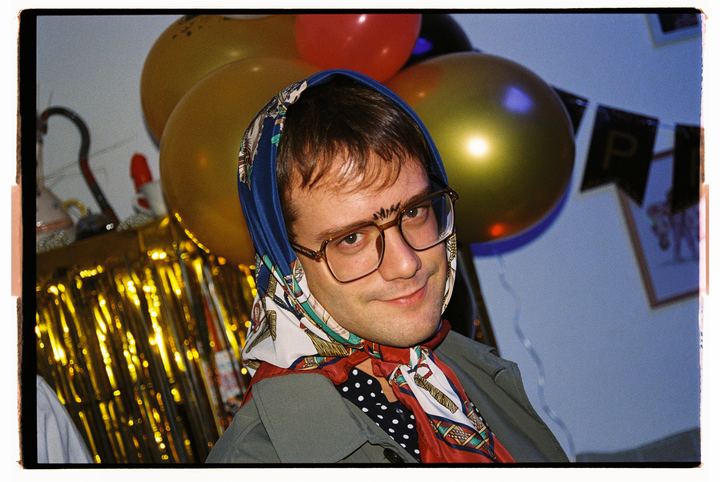 Pelayo con pañuelo en la cabeza entre globos dorados.
